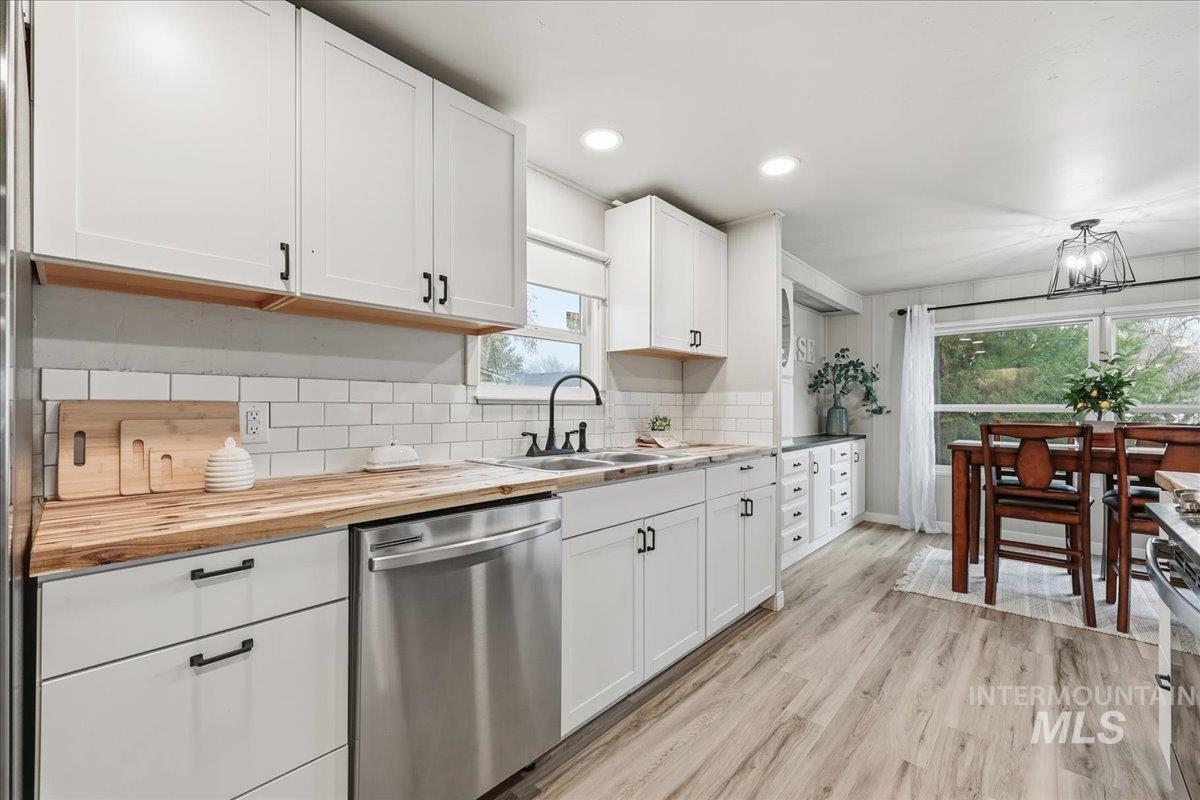 Kitchen featuring appliances with stainless steel finishes, white cabinetry, butcher block countertops, light wood-style flooring, and recessed lighting