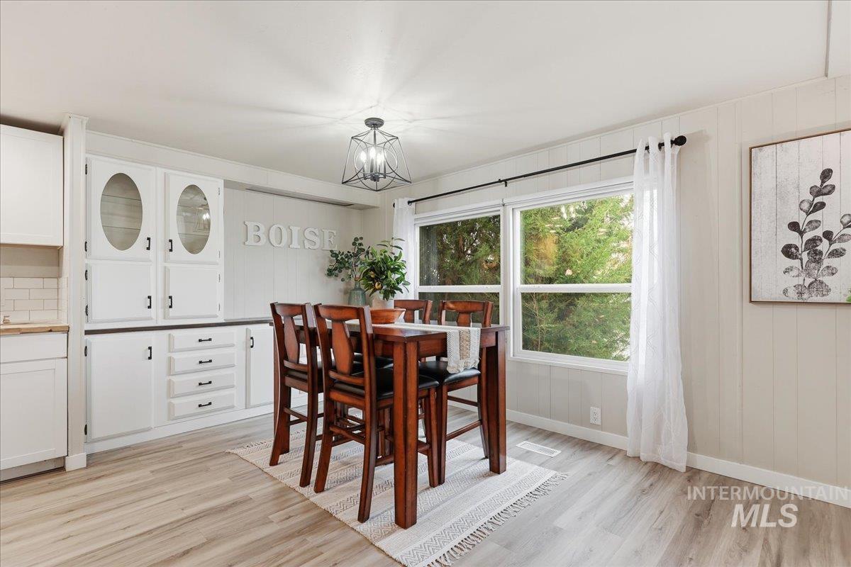 Dining area with light wood-style floors and wood walls