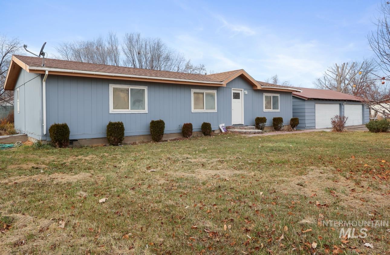 Ranch-style house featuring a front lawn and a shingled roof