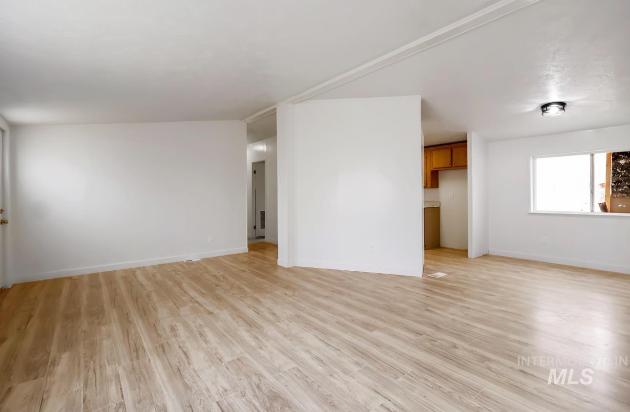 Unfurnished living room featuring light wood finished floors and baseboards