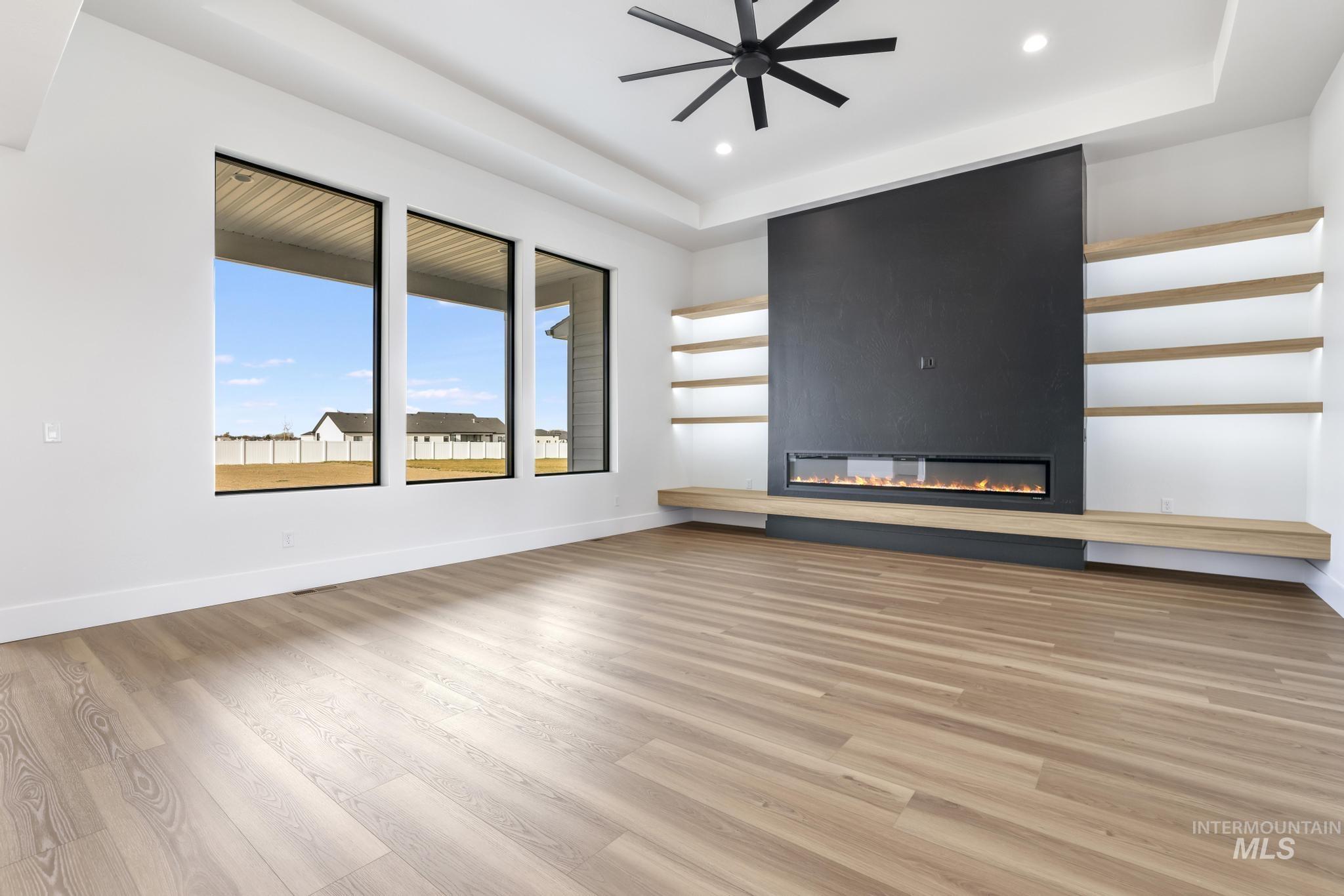 Unfurnished living room with light wood finished floors, a fireplace, recessed lighting, and ceiling fan