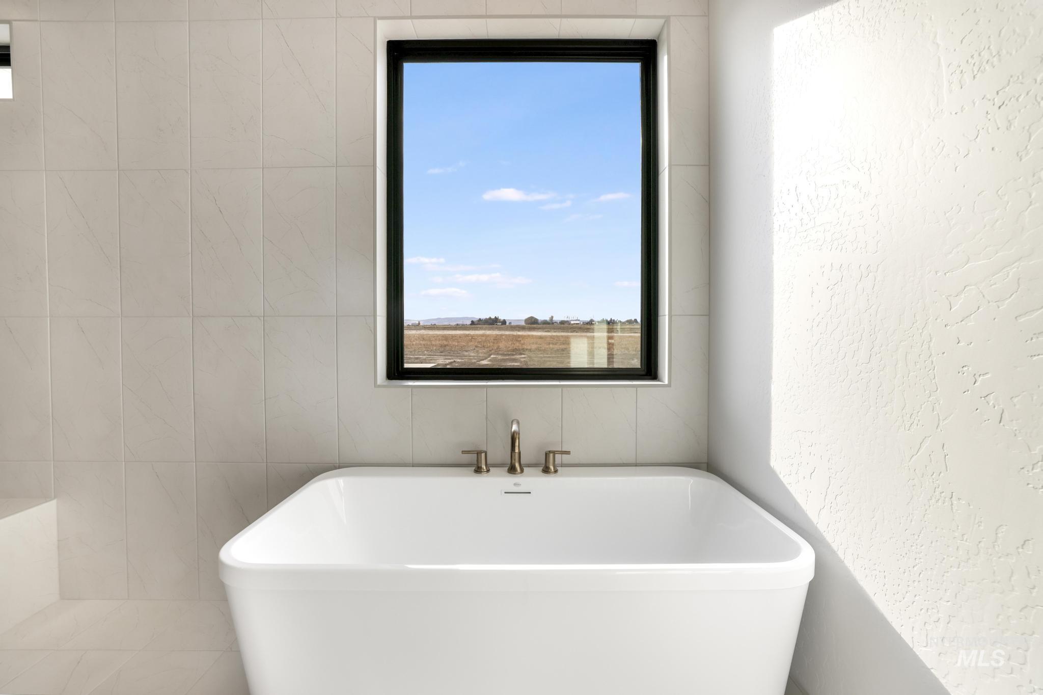 Full bath with a textured wall, a freestanding tub, and tile walls