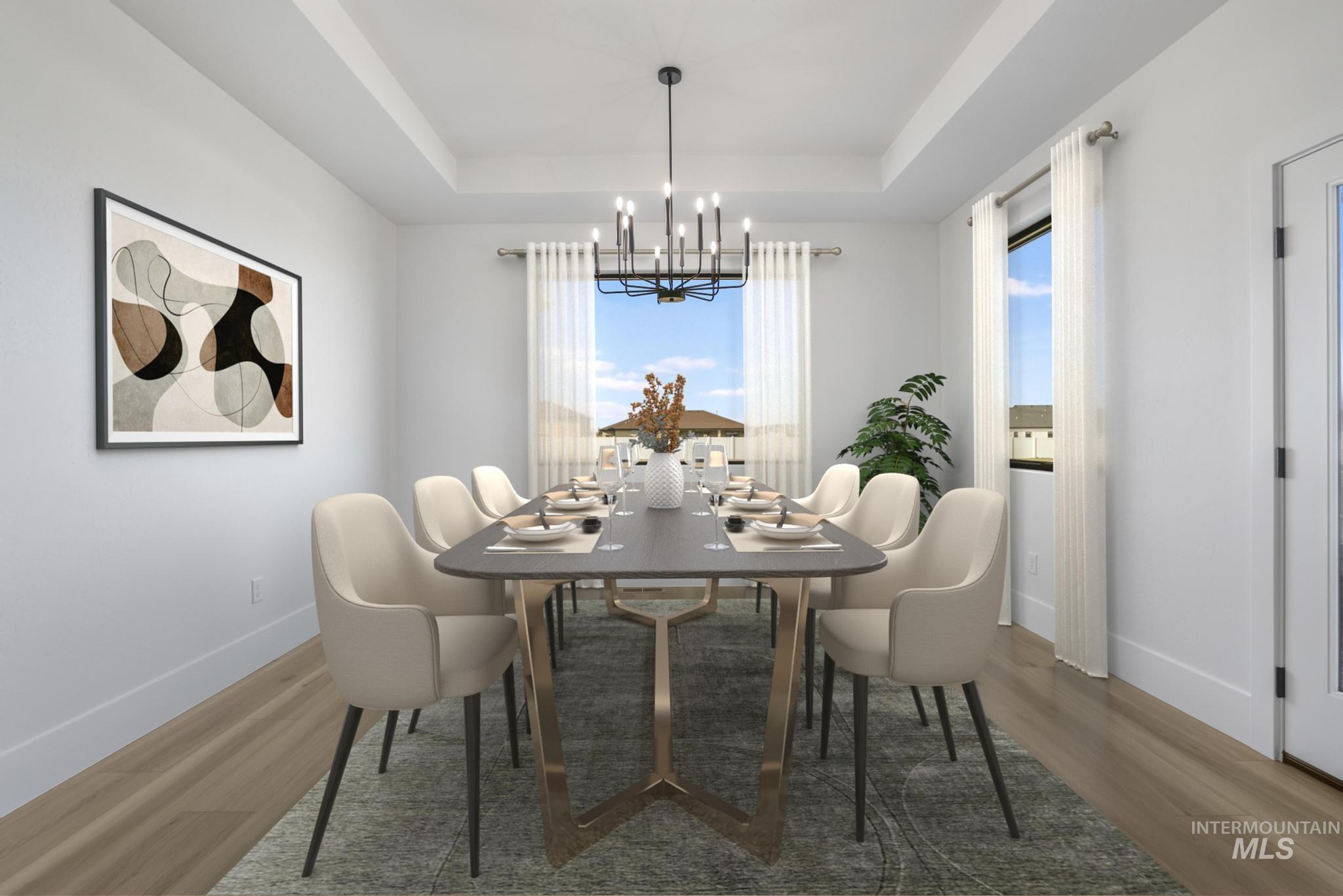 Dining space featuring a chandelier, wood finished floors, plenty of natural light, and a raised ceiling