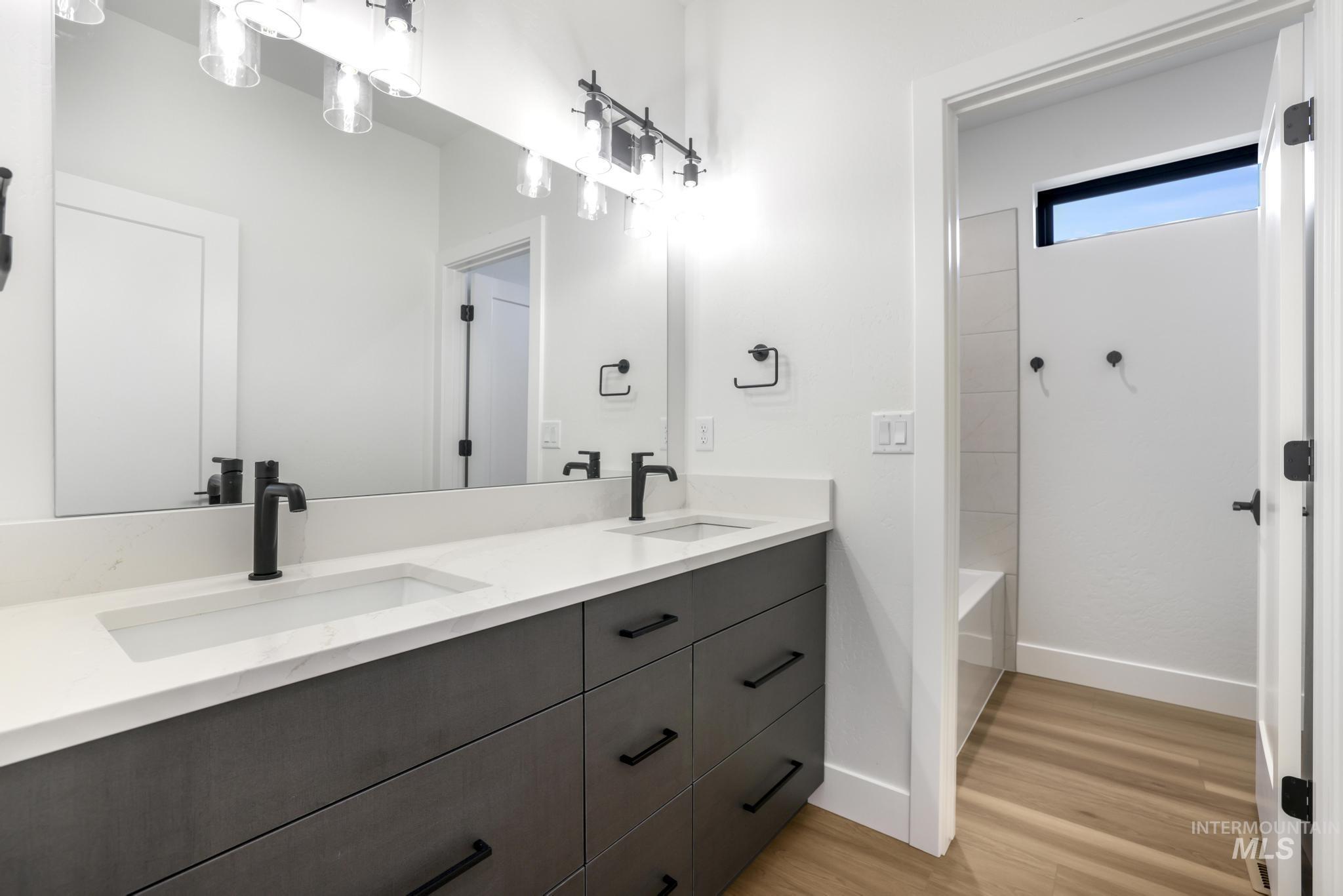 Full bath with double vanity and light wood-style flooring