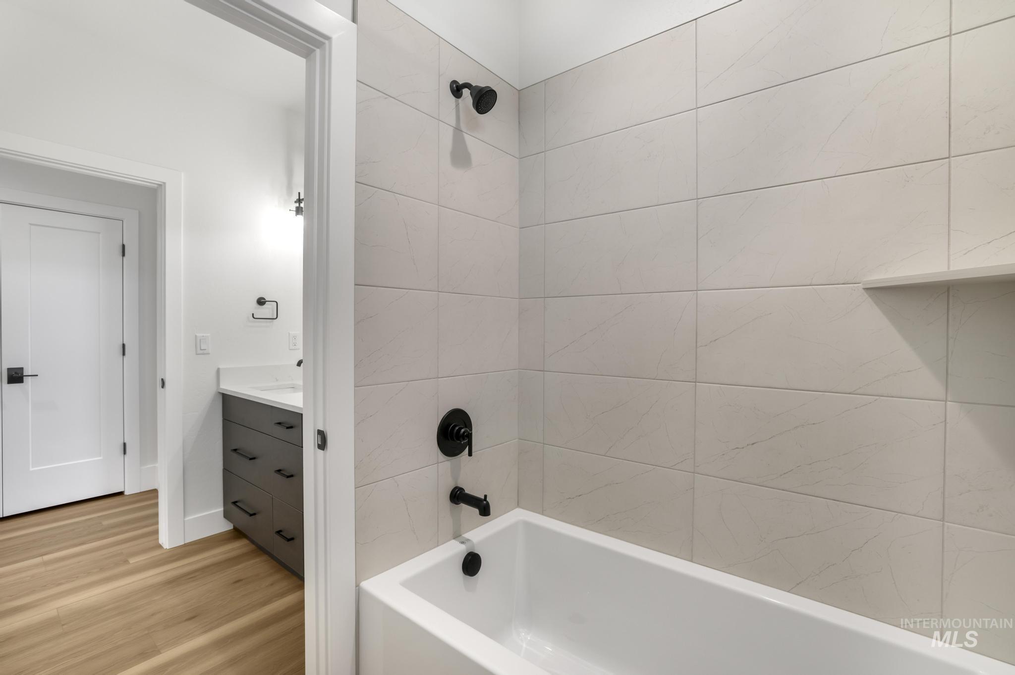Bathroom with vanity, shower / tub combination, and light wood finished floors