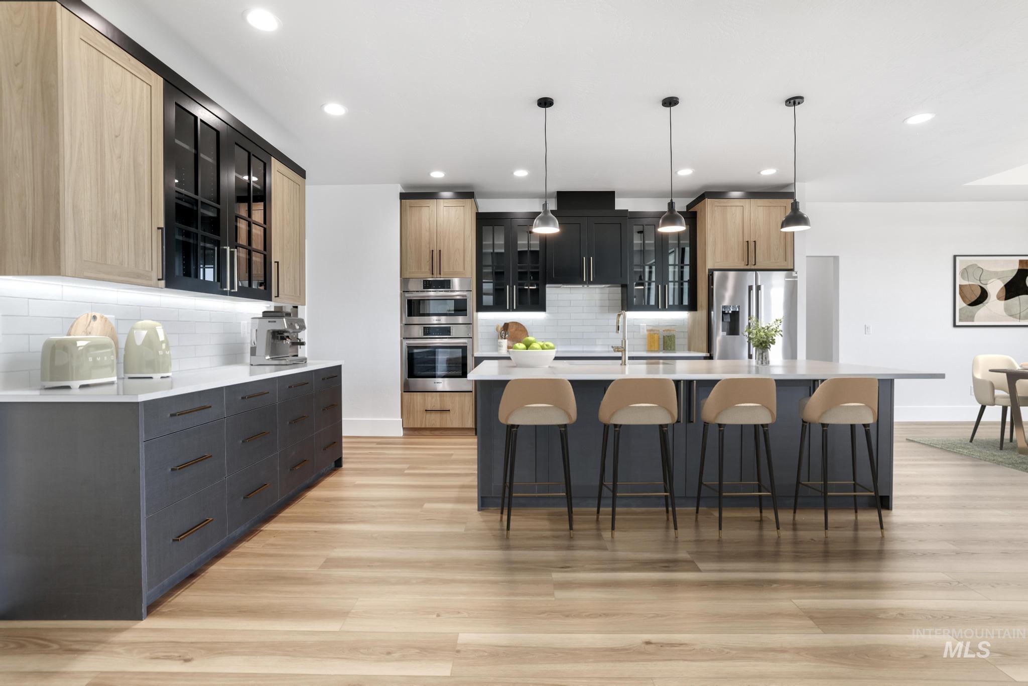 Kitchen featuring a spacious island, glass insert cabinets, a kitchen bar, hanging light fixtures, and recessed lighting