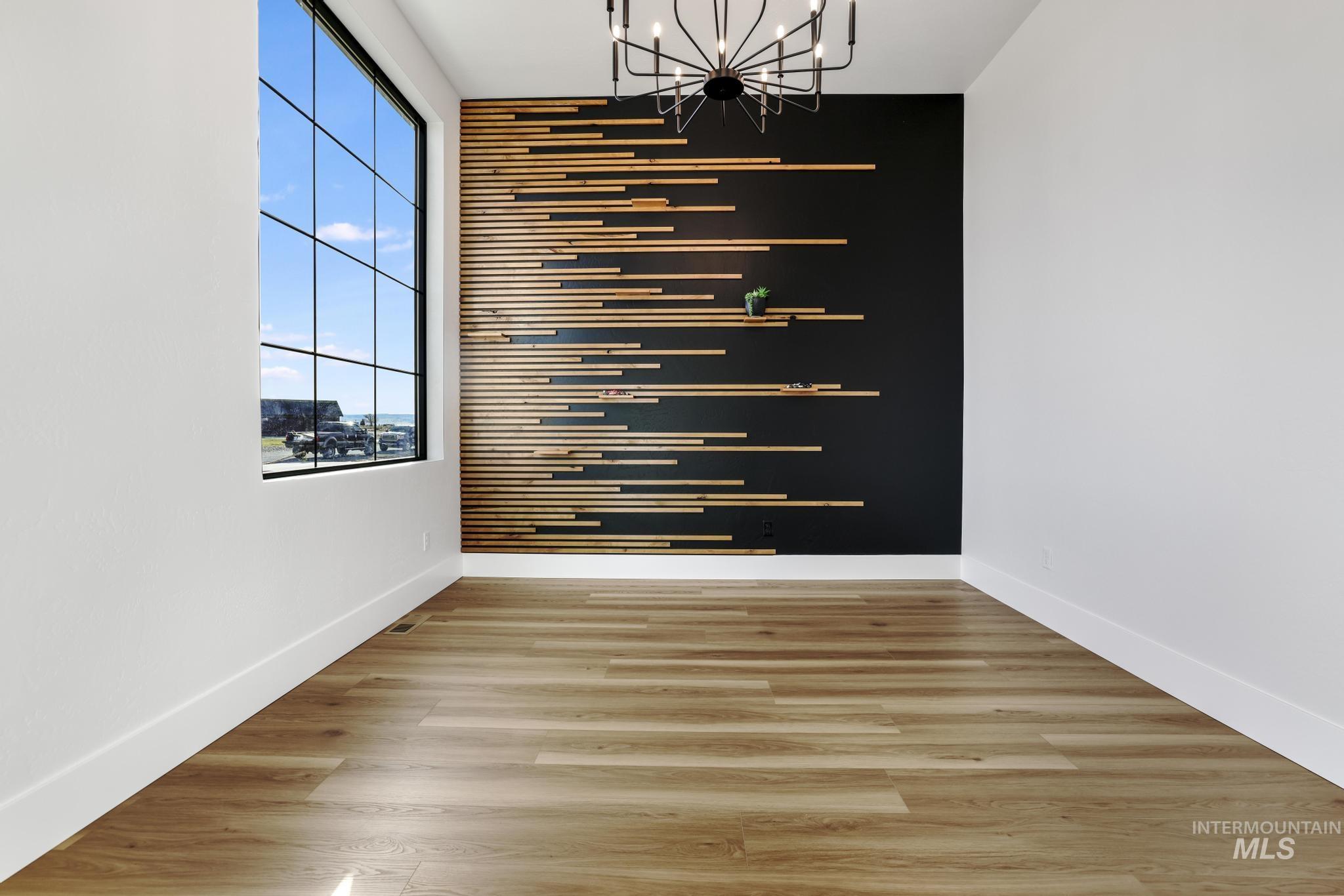 Unfurnished dining area with an accent wall, a chandelier, and light wood-type flooring