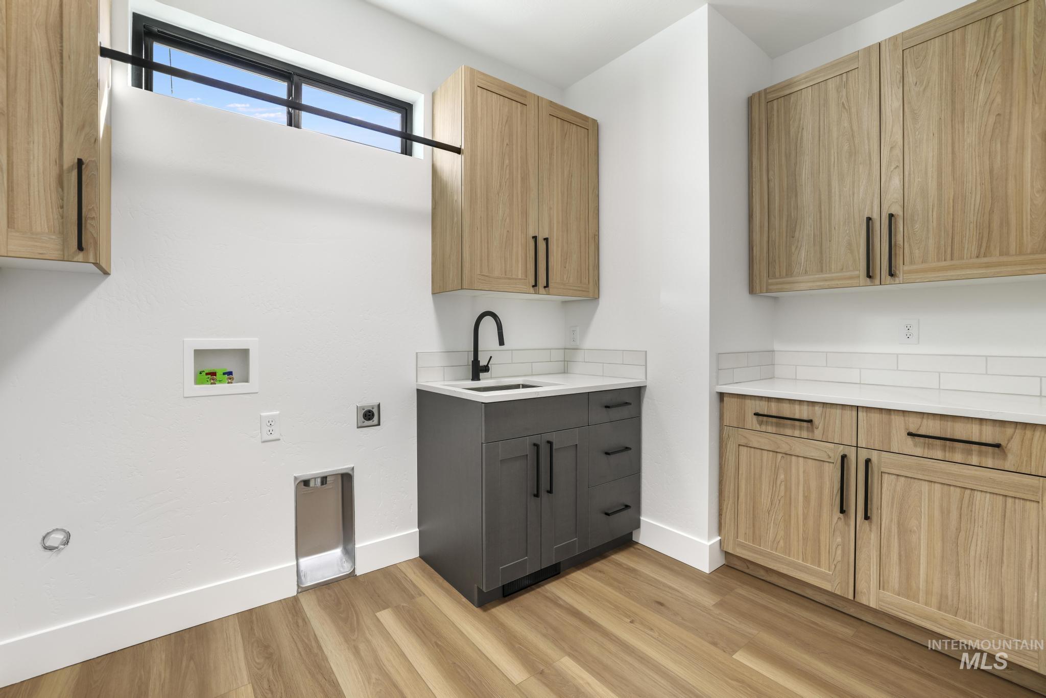 Laundry area featuring hookup for an electric dryer, cabinet space, hookup for a washing machine, and light wood-style floors