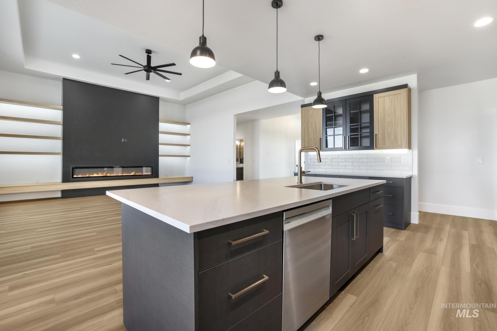 Kitchen with recessed lighting, hanging light fixtures, a center island with sink, stainless steel dishwasher, and tasteful backsplash