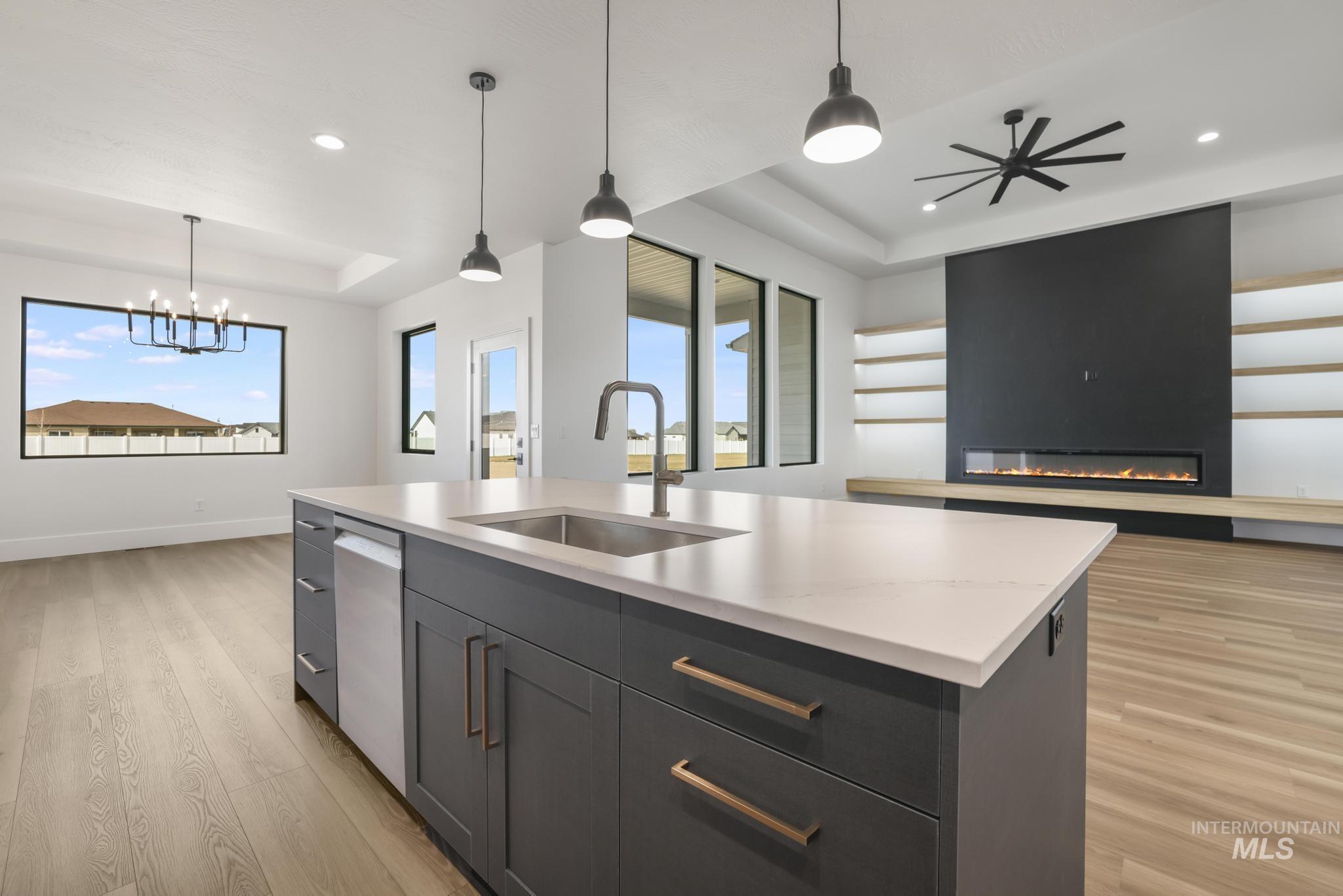 Kitchen featuring decorative light fixtures, open floor plan, light wood-style floors, a kitchen island with sink, and recessed lighting
