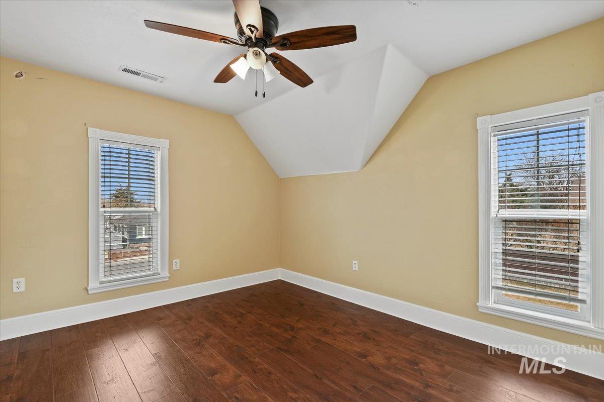 Additional living space with dark wood-style floors, ceiling fan, and lofted ceiling