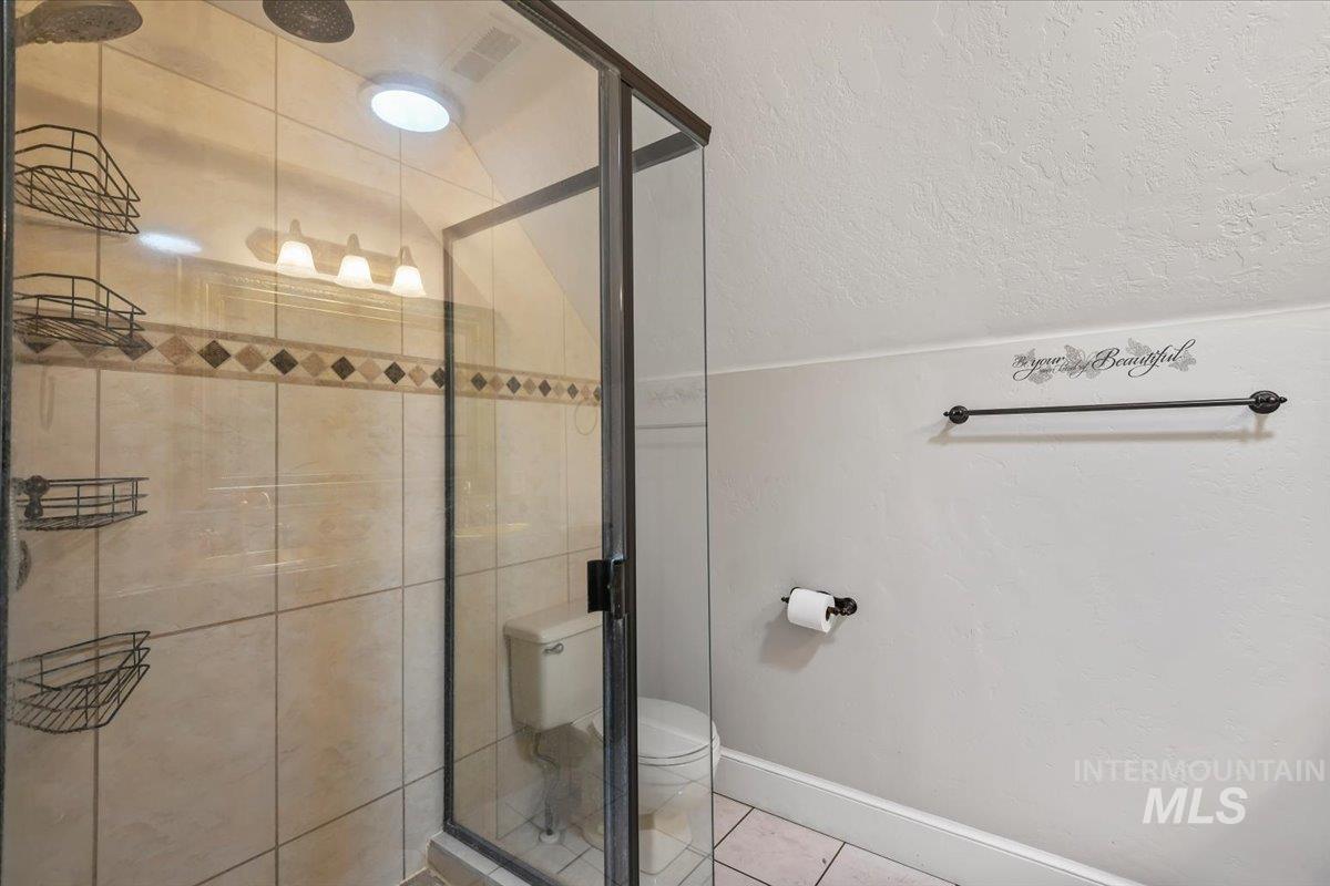Full bath with a shower stall, a textured ceiling, and tile patterned flooring