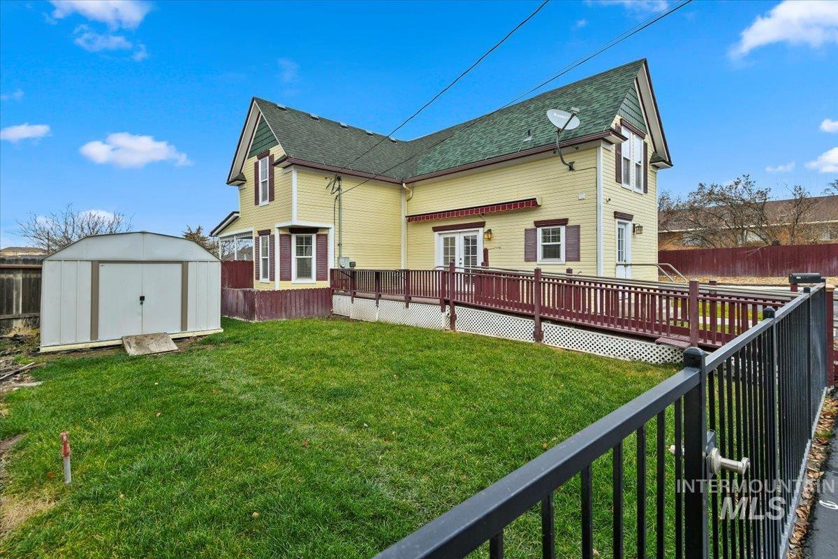 Back of property featuring a fenced backyard, a shed, a wooden deck, and a shingled roof