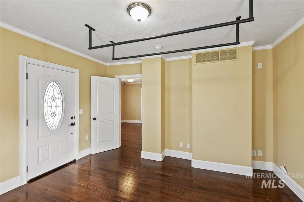 Foyer entrance with dark wood-style floors, ornamental molding, and a textured ceiling