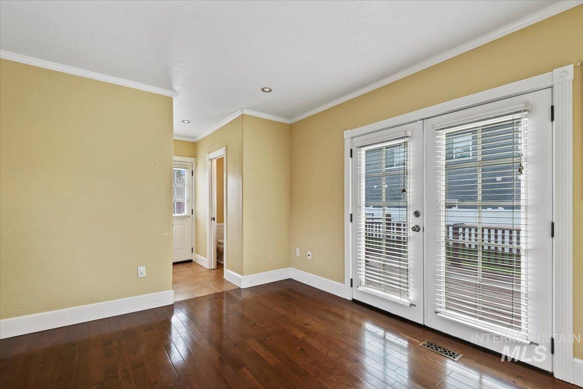 Unfurnished room with french doors, dark wood-type flooring, plenty of natural light, and crown molding