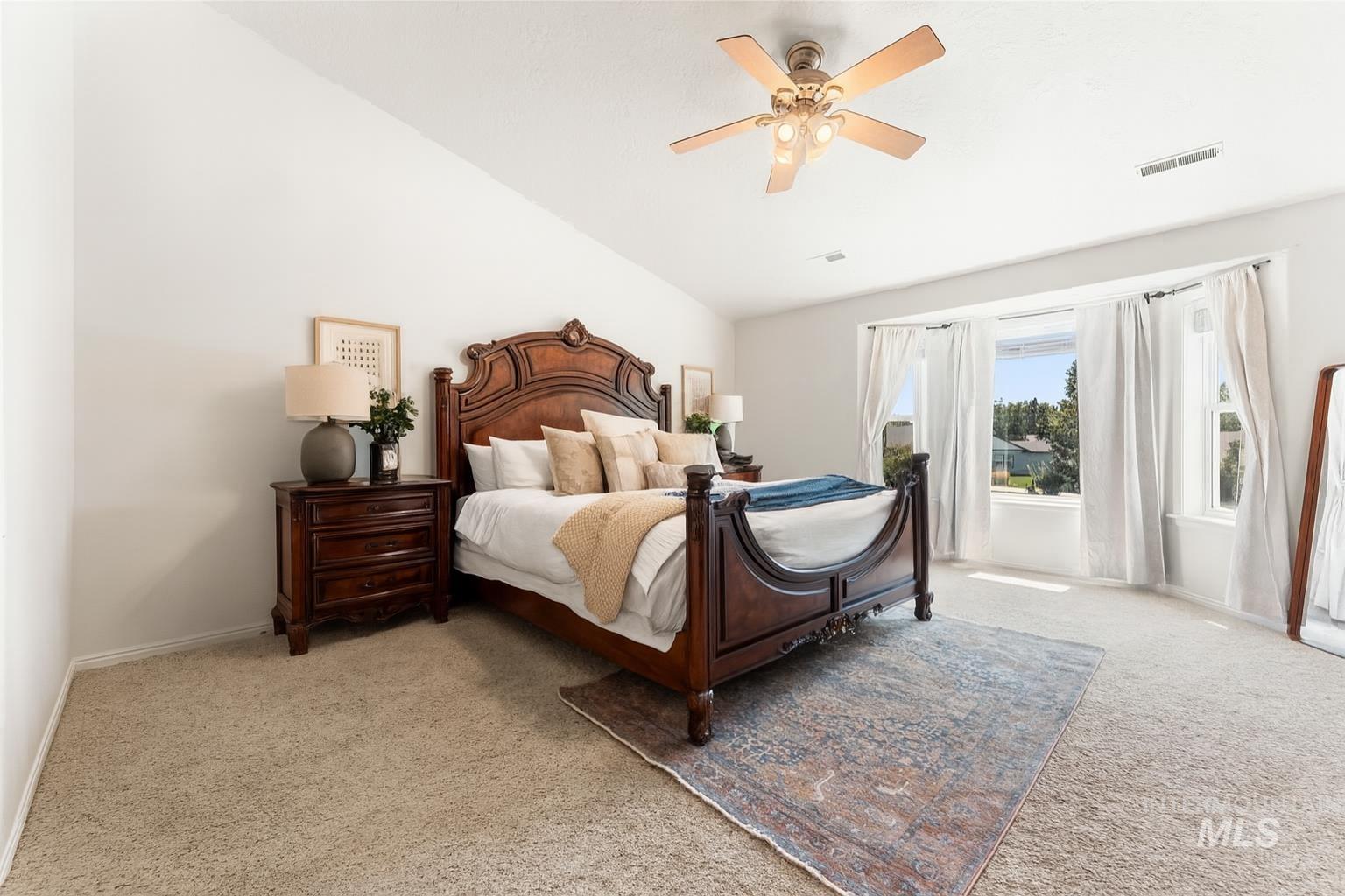 Carpeted bedroom featuring lofted ceiling and ceiling fan