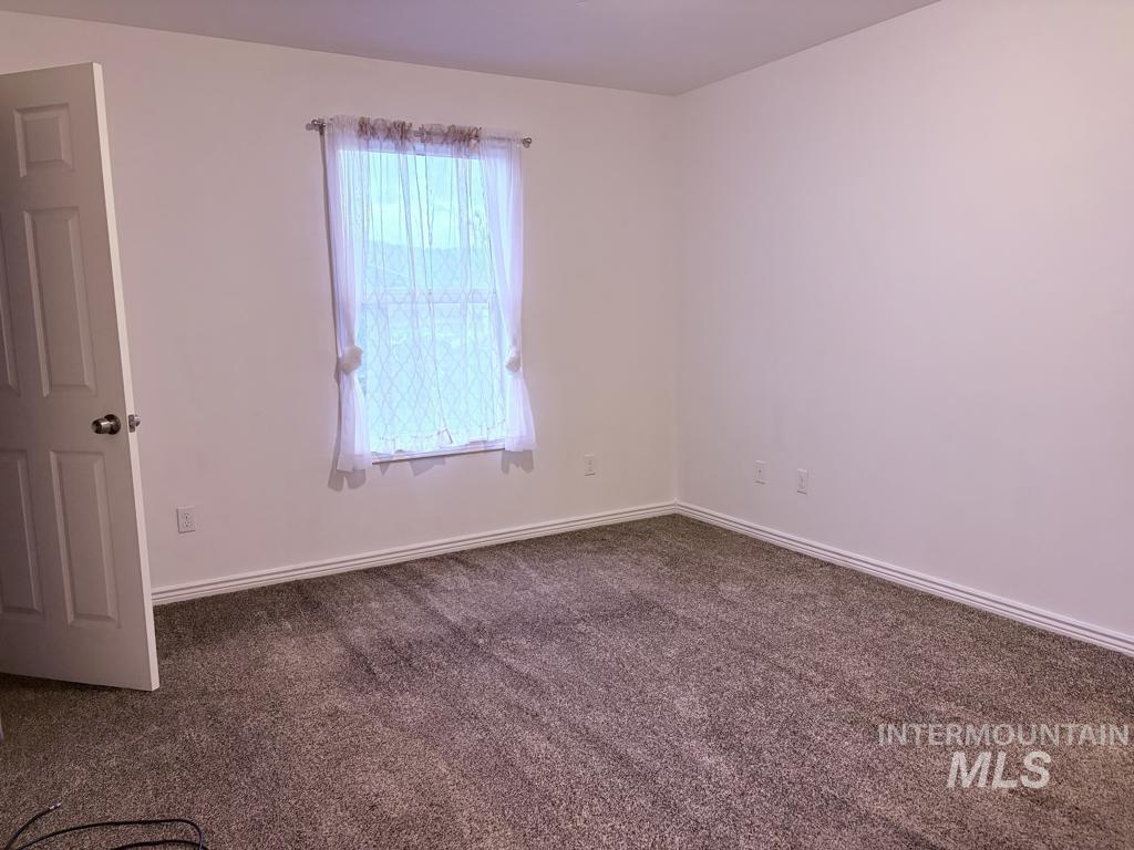 Empty room with dark carpet and baseboards