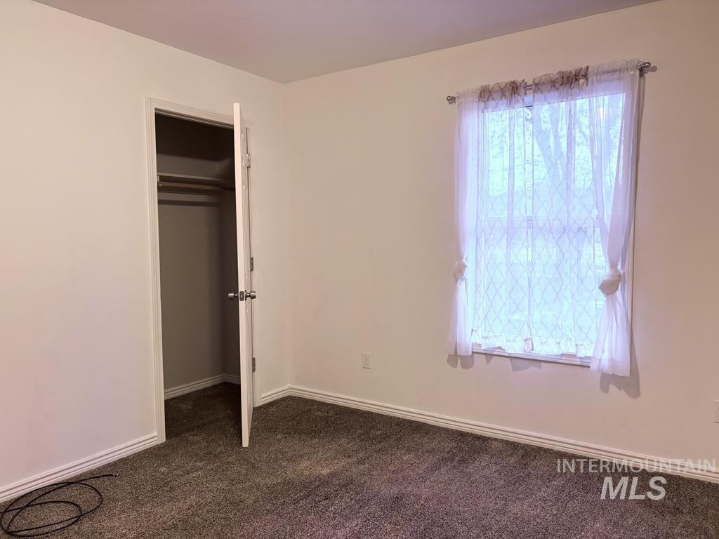 Unfurnished bedroom with dark carpet and a closet