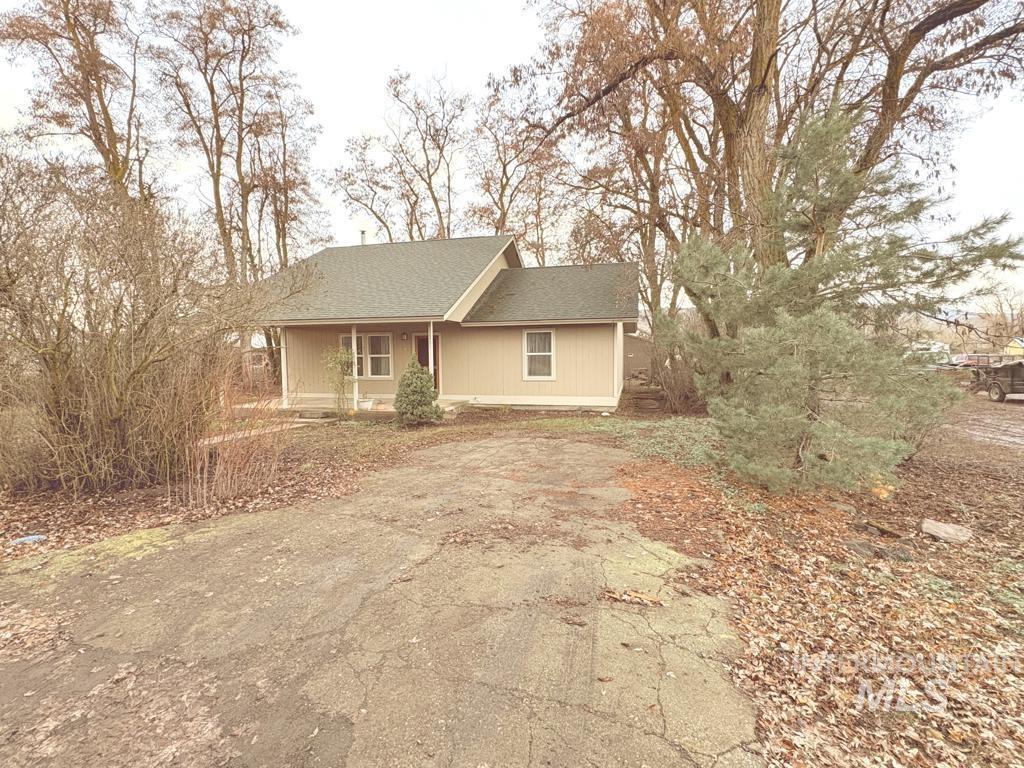 Single story home with a porch, a shingled roof, and asphalt driveway