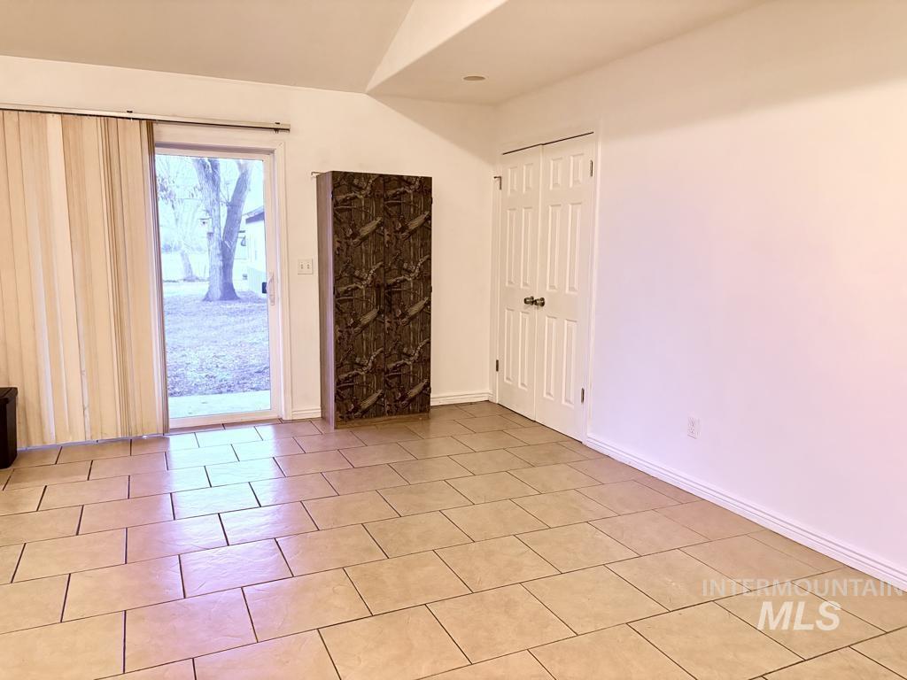 Empty room featuring light tile patterned flooring and vaulted ceiling
