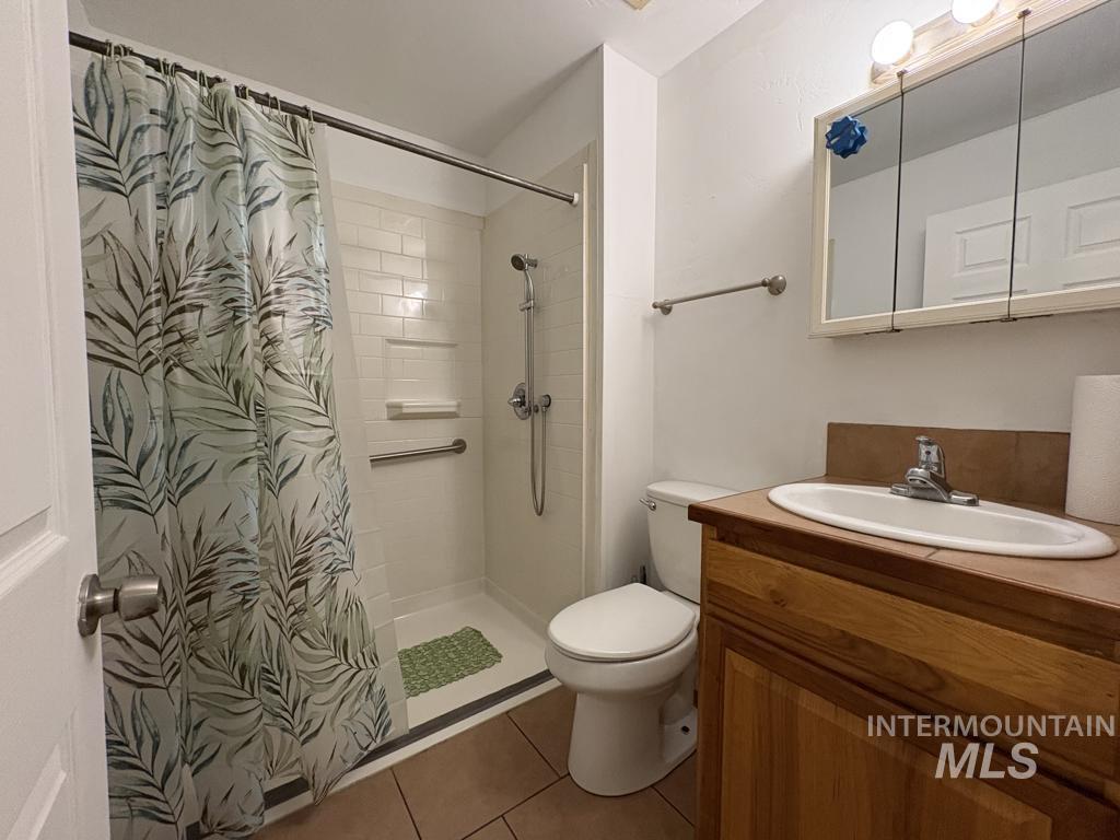 Bathroom featuring vanity, a tile shower, and tile patterned flooring