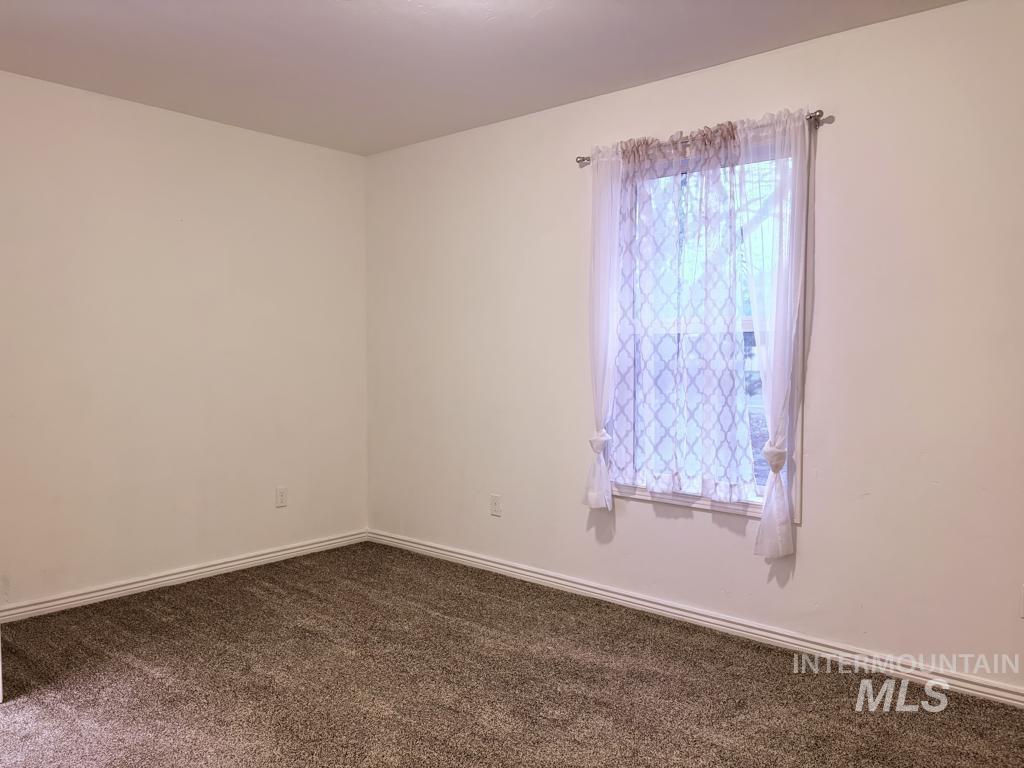 Empty room with dark colored carpet and baseboards