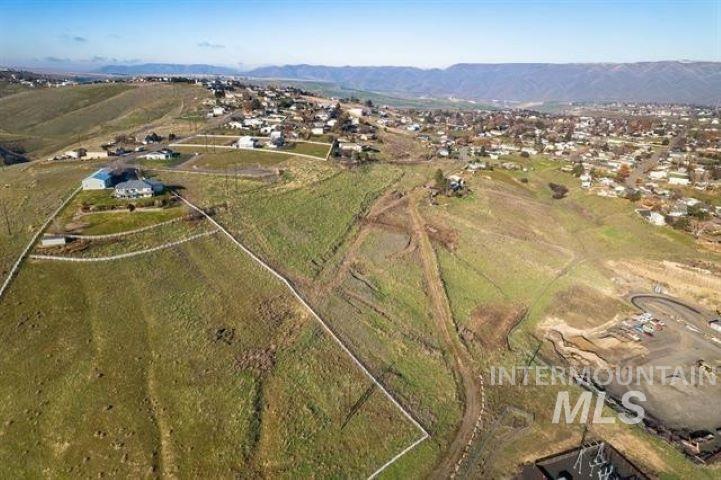 Aerial view of property and surrounding area featuring rural landscape and a mountain backdrop