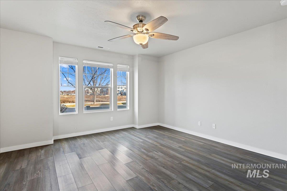 Empty room featuring dark wood-type flooring and a ceiling fan