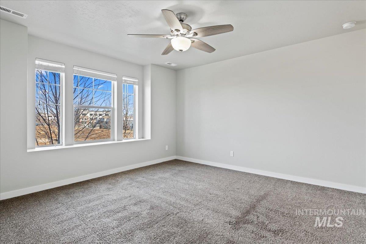 Carpeted spare room featuring baseboards and a ceiling fan