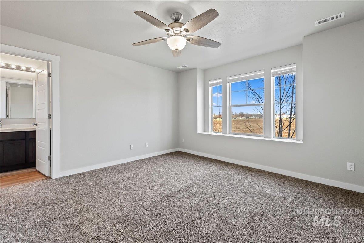 Unfurnished bedroom with light colored carpet, ceiling fan, and ensuite bath