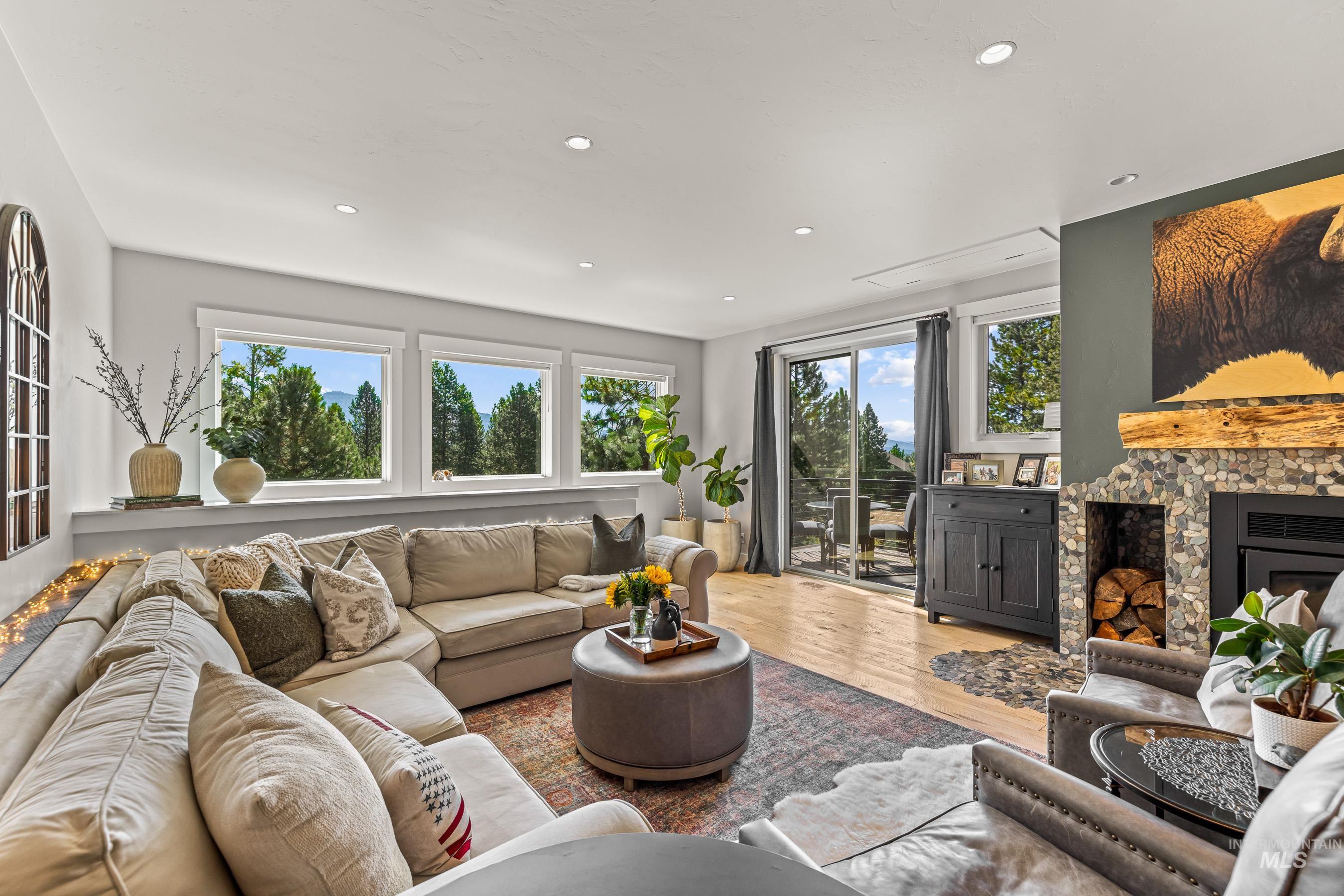 Living room featuring light wood-type flooring, a fireplace, healthy amount of natural light, and recessed lighting