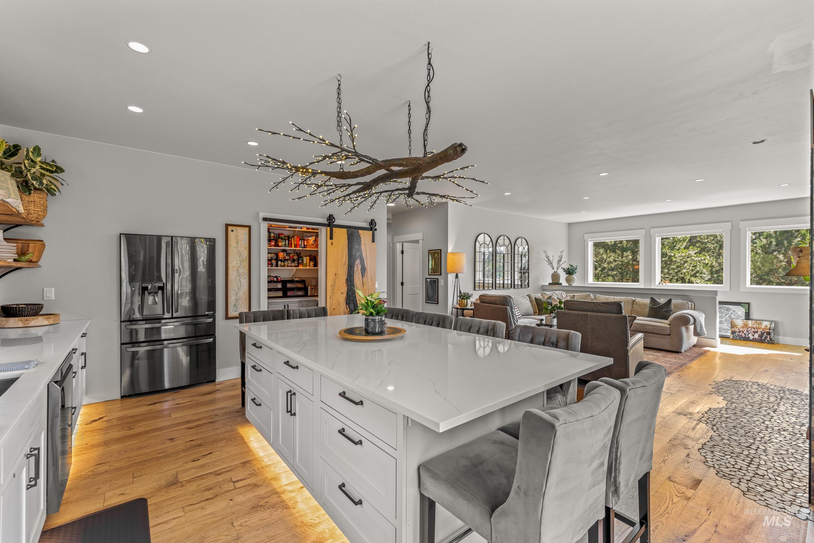 Kitchen with a barn door, white cabinetry, recessed lighting, light stone counters, and a kitchen bar