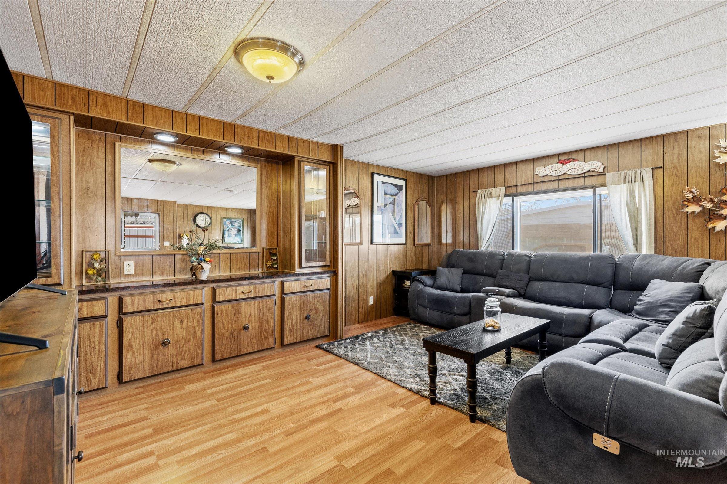 Living area with wood walls, light wood finished floors, and a textured ceiling