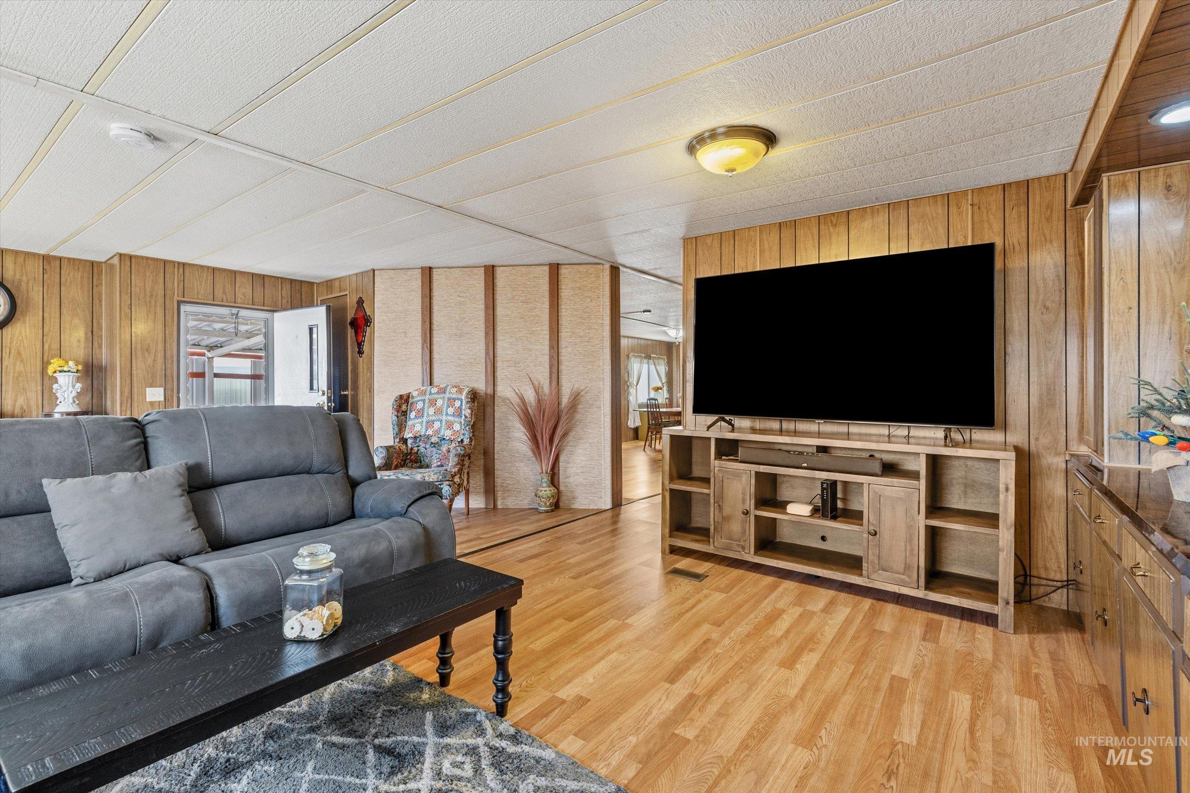Living room with wooden walls and light wood-style flooring