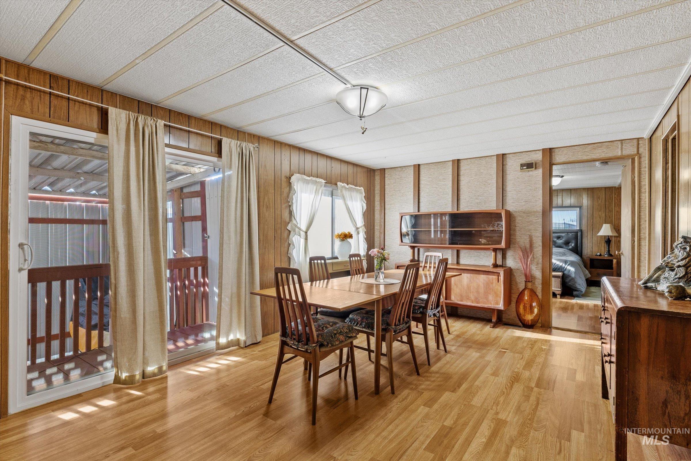 Dining space with light wood-style flooring and wood walls