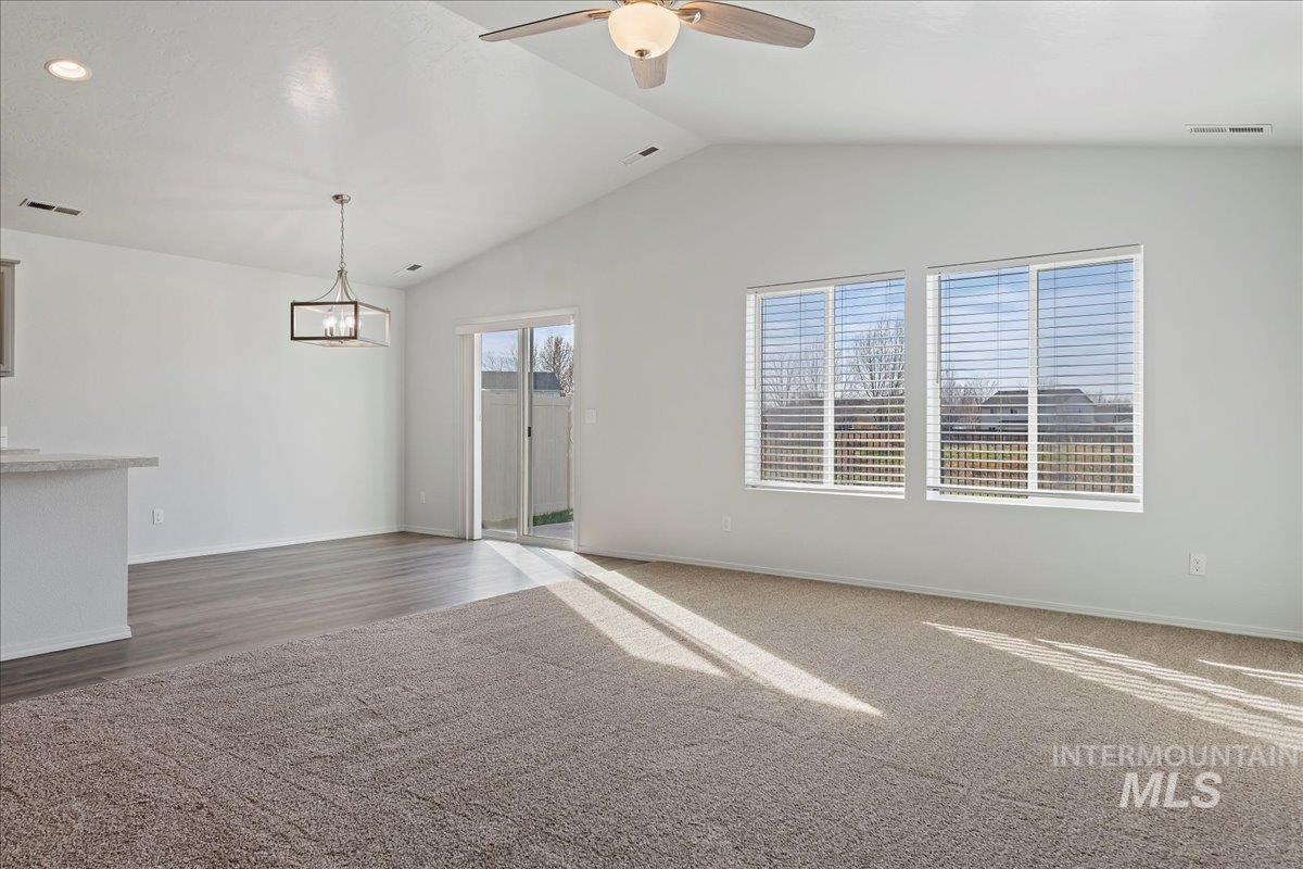 Unfurnished living room with a ceiling fan and vaulted ceiling