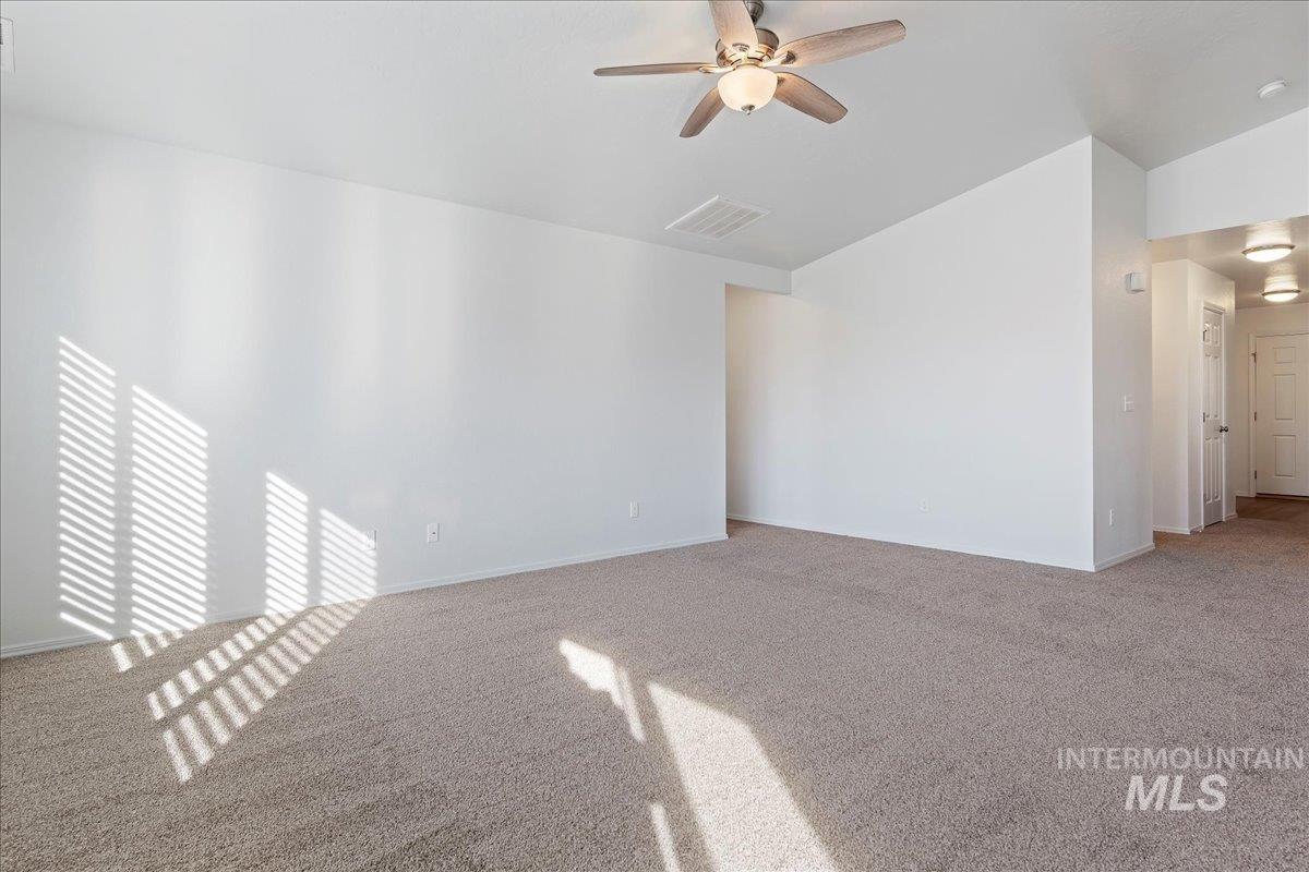 Spare room featuring light colored carpet, ceiling fan, and vaulted ceiling