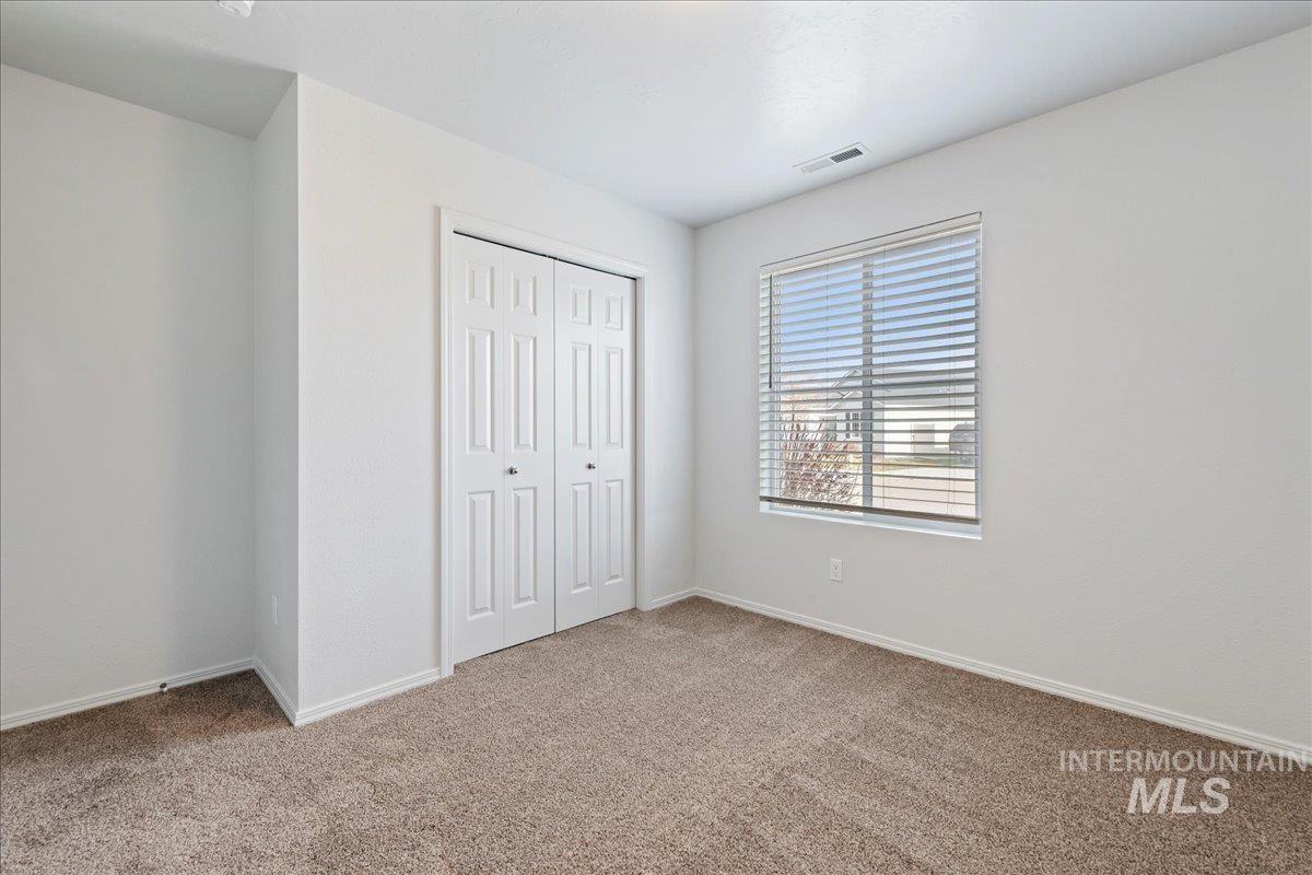 Unfurnished bedroom with light carpet and a closet