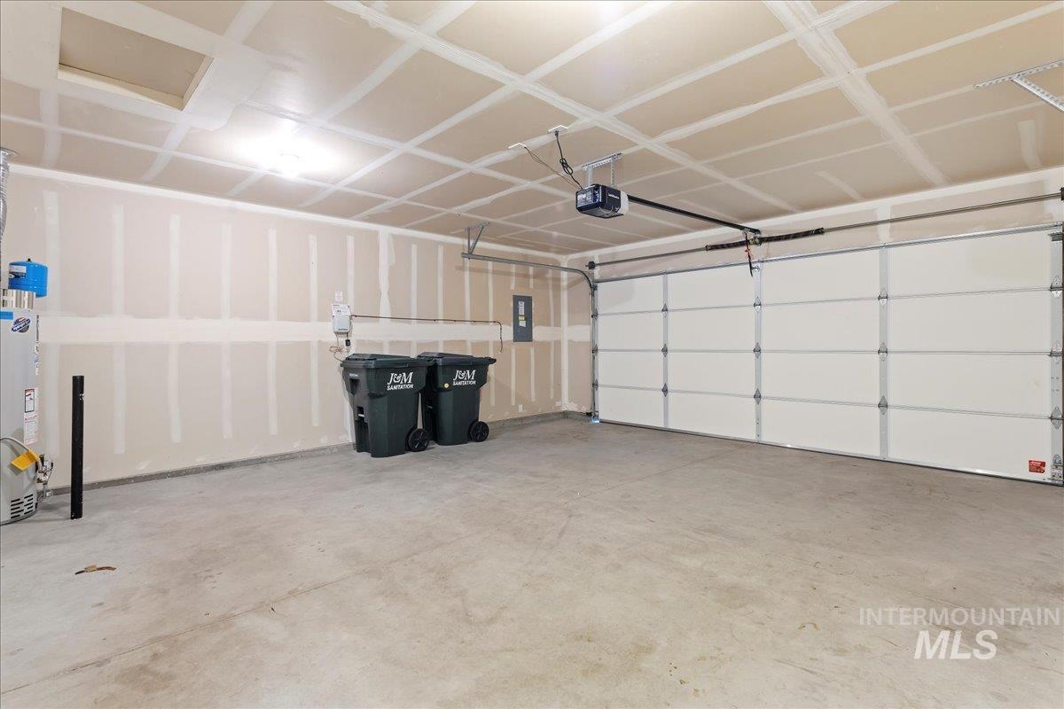 Garage featuring water heater, electric panel, and a garage door opener