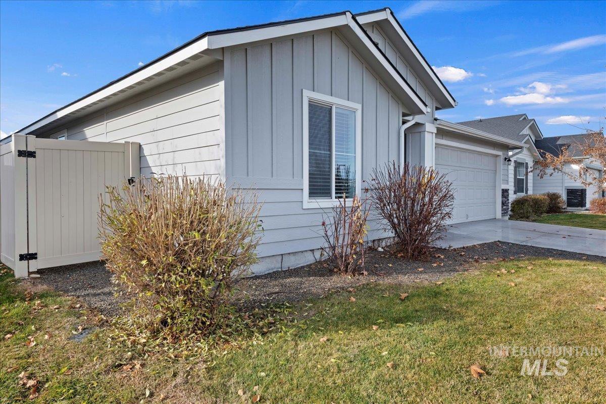 View of home's exterior featuring board and batten siding, an attached garage, concrete driveway, and a yard