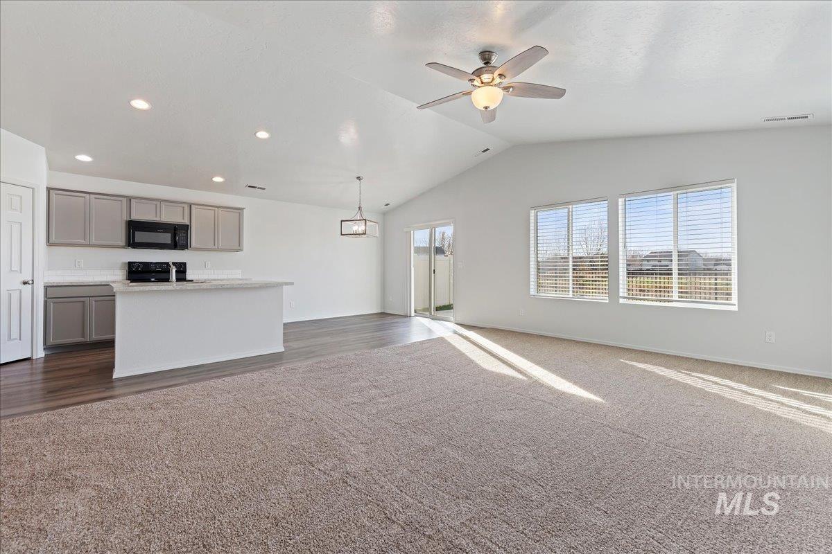 Unfurnished living room with vaulted ceiling, ceiling fan, recessed lighting, and dark carpet