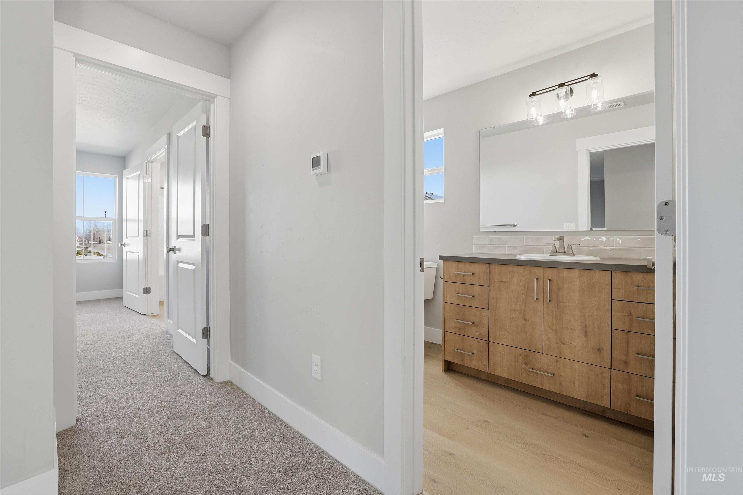Corridor featuring healthy amount of natural light and light colored carpet