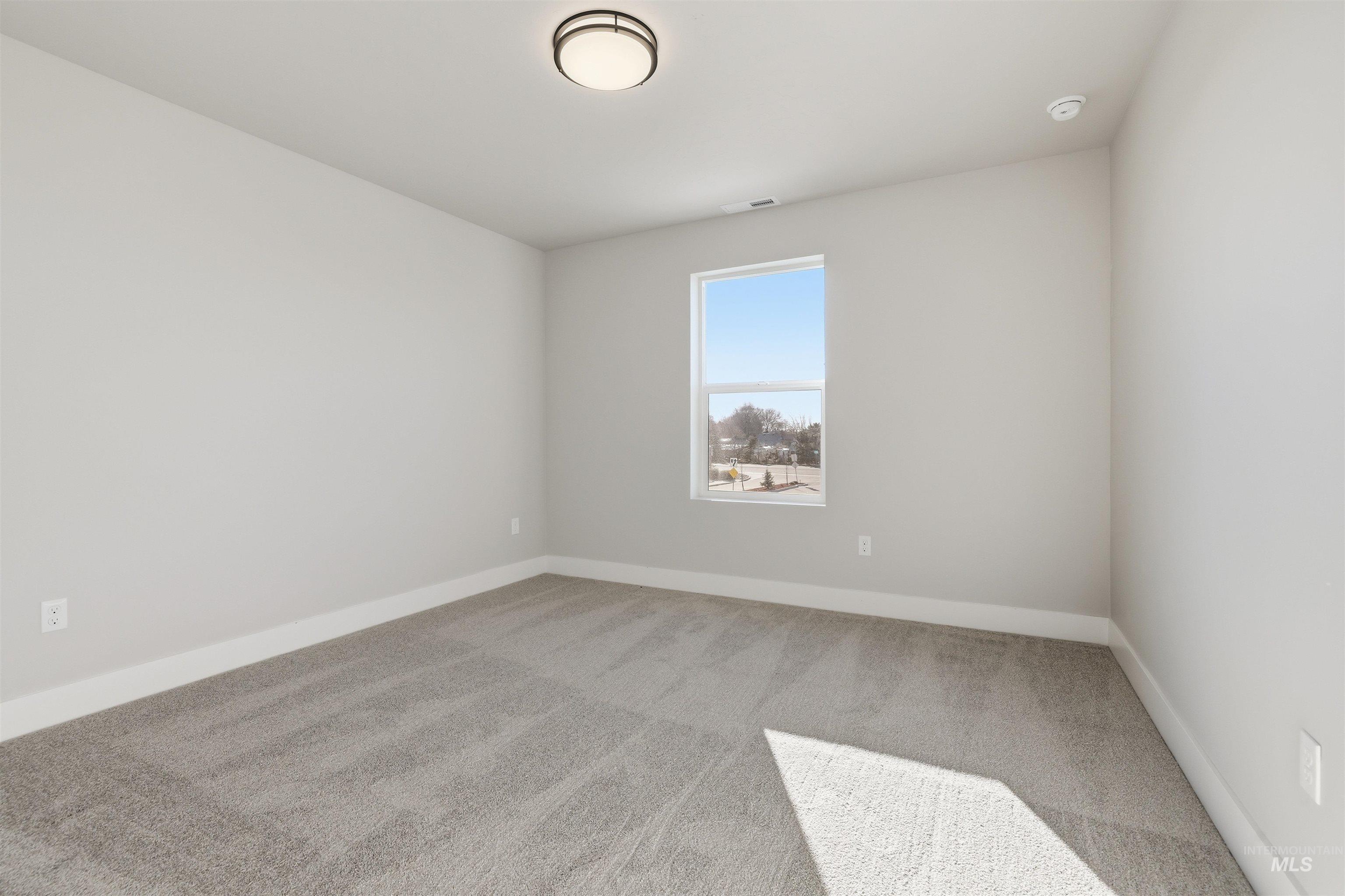 Empty room with light colored carpet and baseboards