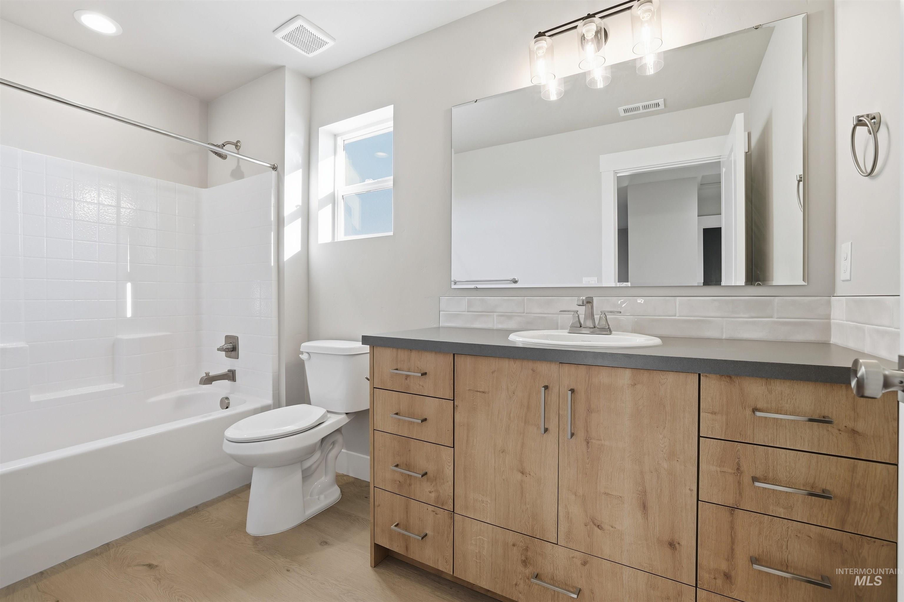 Full bath with vanity, bathtub / shower combination, tasteful backsplash, and light wood-style floors
