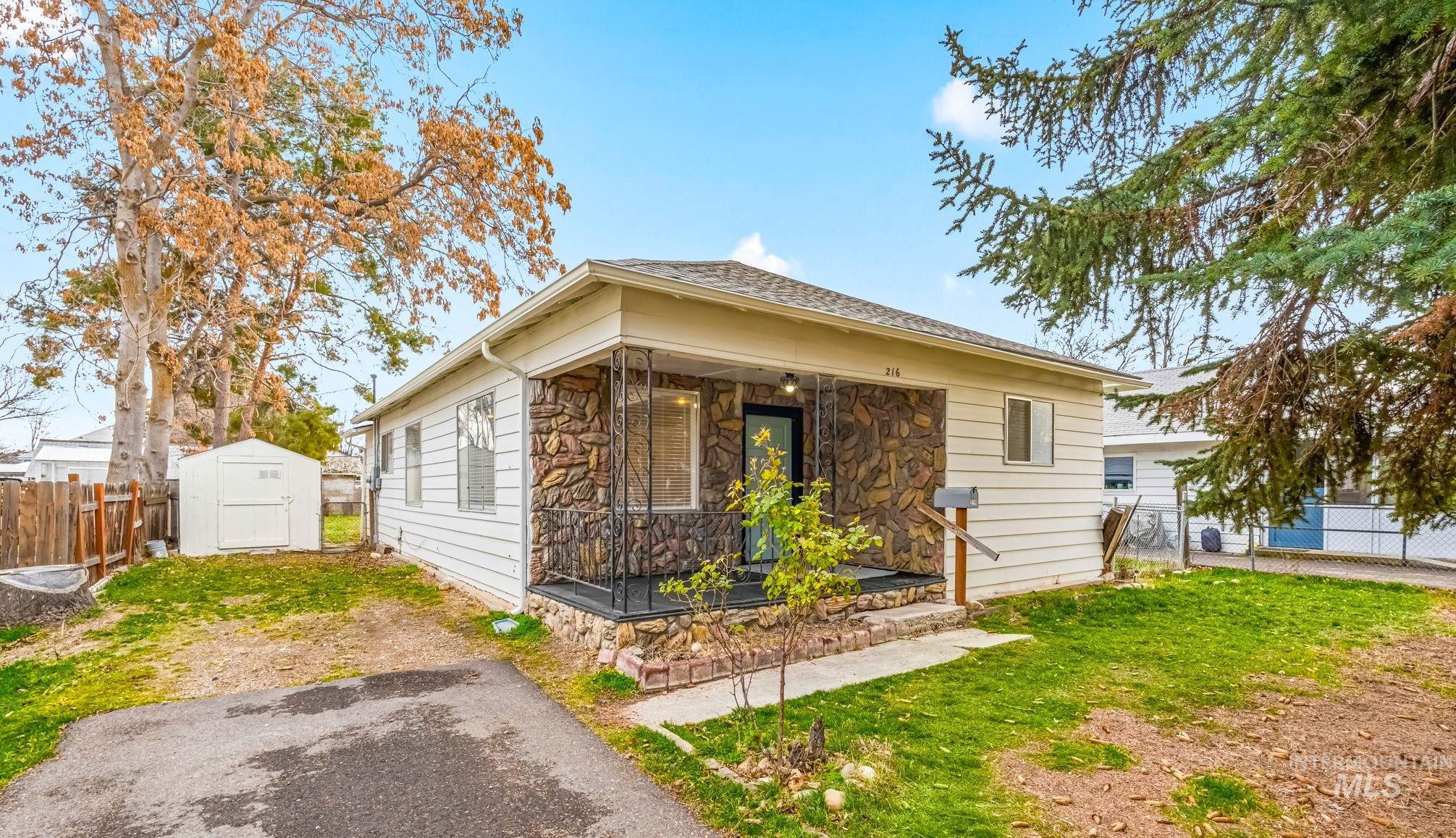 View of front of property with stone siding, a storage unit, and a porch