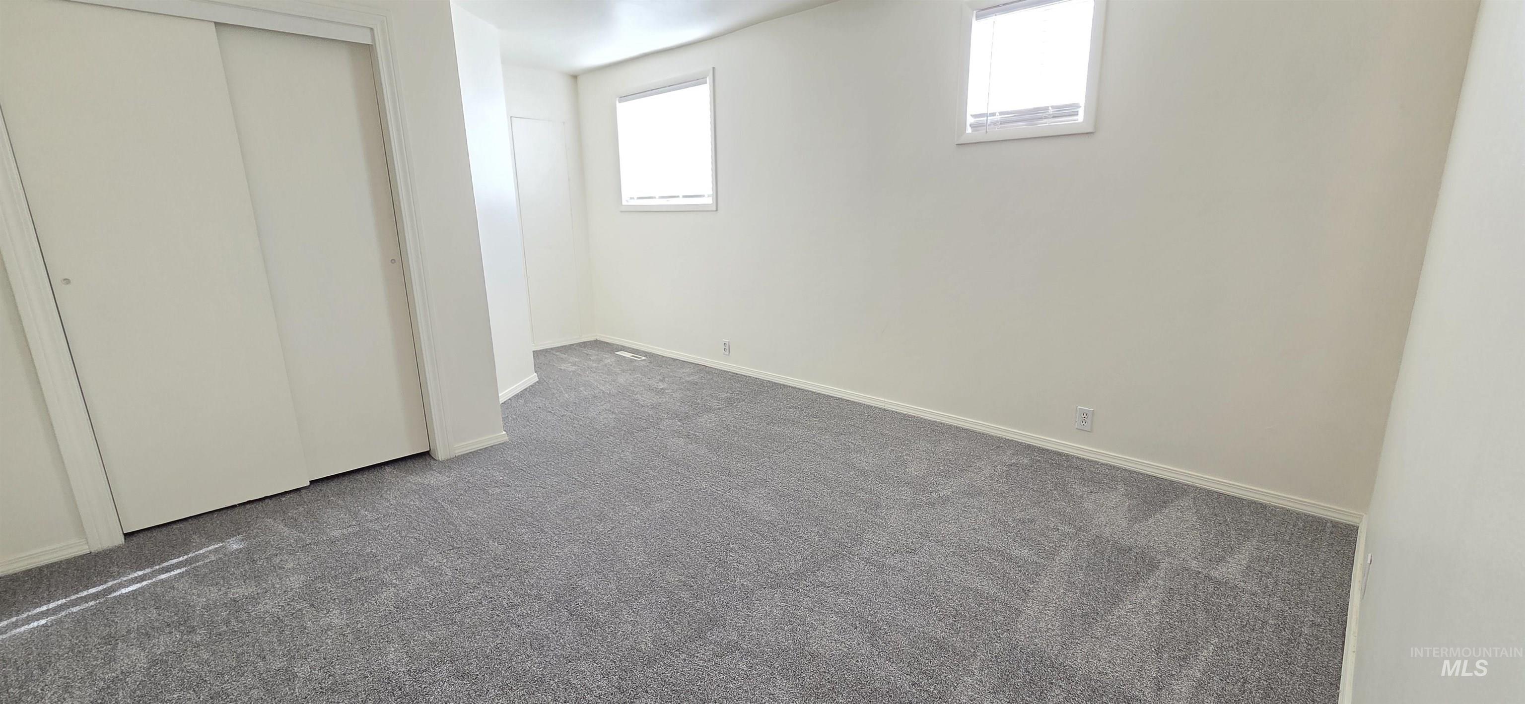 Unfurnished bedroom featuring dark carpet and a closet
