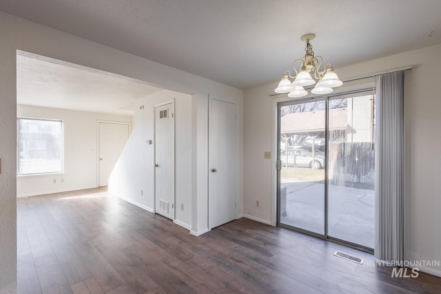 Unfurnished dining area with dark wood finished floors, healthy amount of natural light, and a chandelier