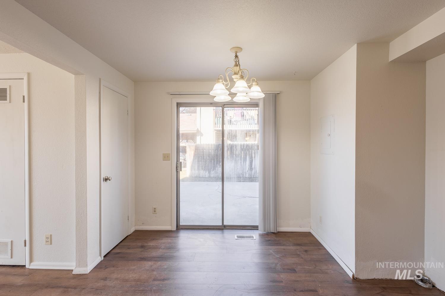 Unfurnished dining area featuring dark wood-style floors and a chandelier