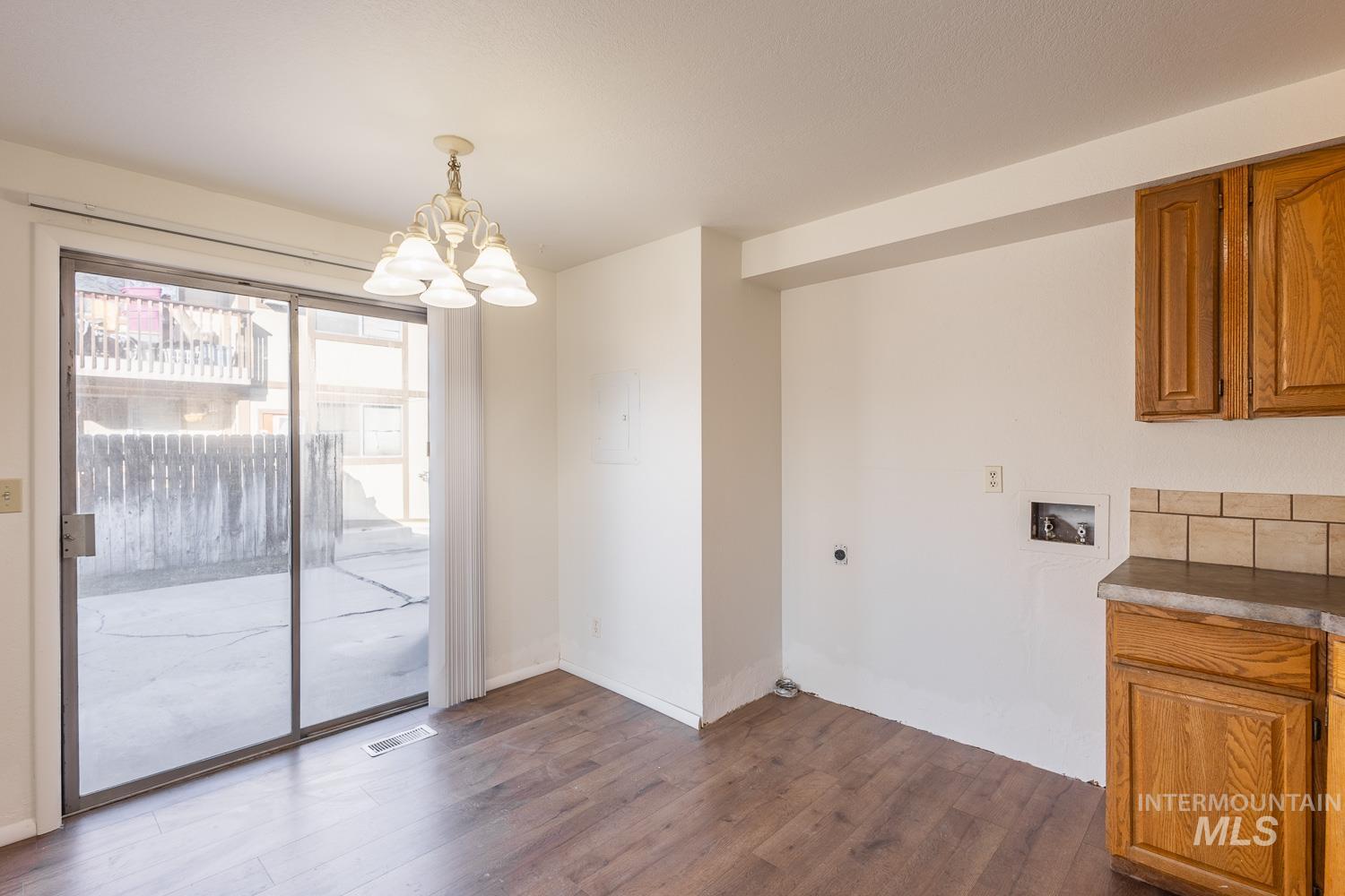 Unfurnished dining area featuring a chandelier and dark wood-style floors