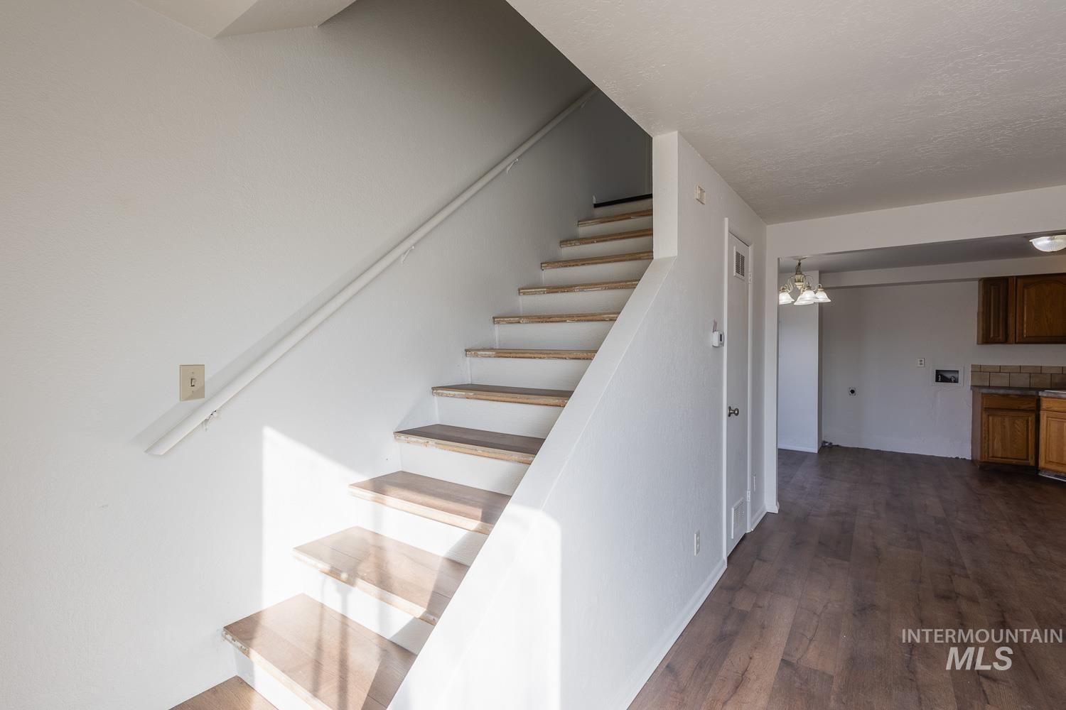 Staircase with a chandelier and wood finished floors